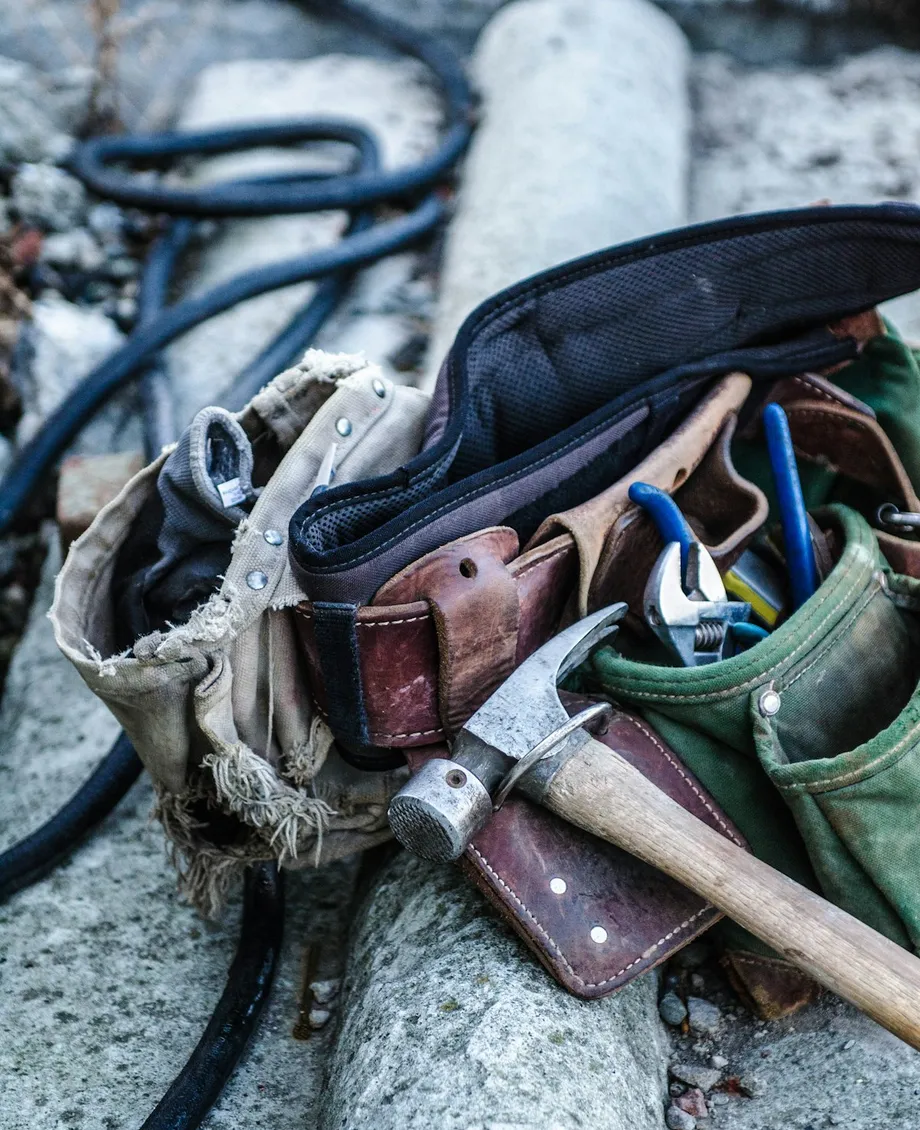 Close-up of a contractor's hammer and tool belt on a wood workbench